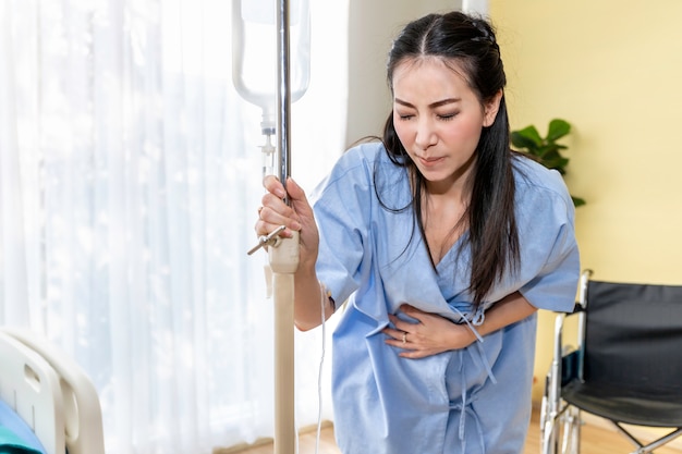 Young Asian woman patient walking and period pain in the hospital room.