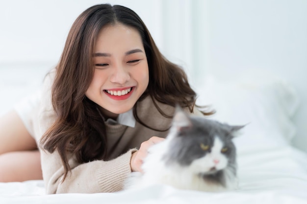 家で猫と遊ぶ若いアジアの女性