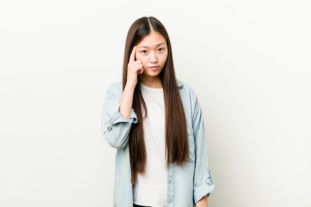 Young asian woman pointing his temple with fingers