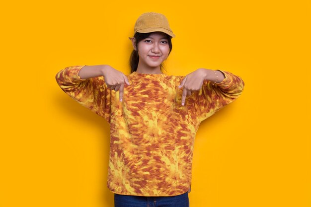 young asian woman pointing with fingers to different directions isolated on yellow background