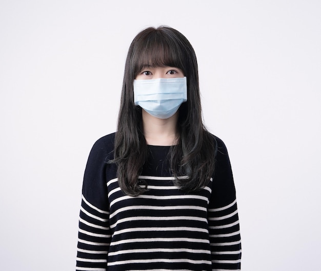 Ritratto di giovane donna asiatica che indossa una maschera medica chirurgica blu per prevenire infezioni inquinamento atmosferico malato isolato su sfondo bianco spazio copia primo piano ritagliato
