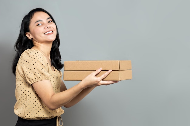 Young asian woman posing holding a pizza box side view