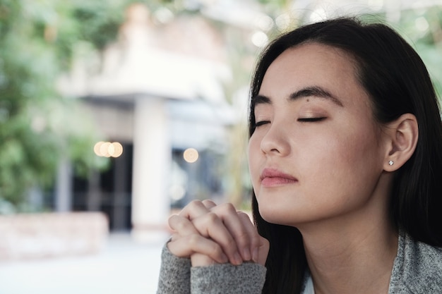 若いアジア人女性が目を閉じて祈った