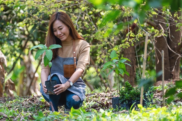 庭に木を植える準備をしている若いアジアの女性