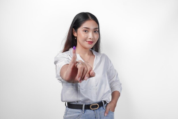 Молодая азиатка с гордостью показывает маленький палец, погруженный в фиолетовое чернила после голосования на президентских и парламентских выборах, выражая волнение и счастье