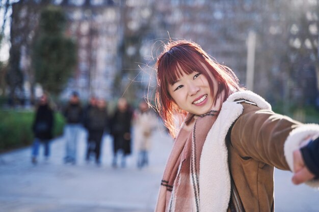 사진 도시 거리에서 남자의 팔을 당기는 젊은 아시아 여자