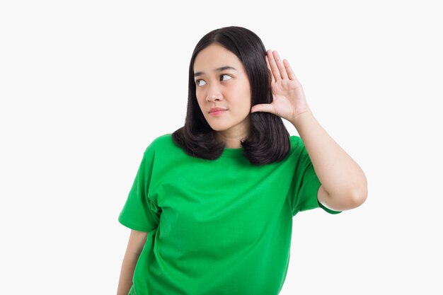 写真 若いアジア人の女性が耳に手を当てて会話か何かを聞いている