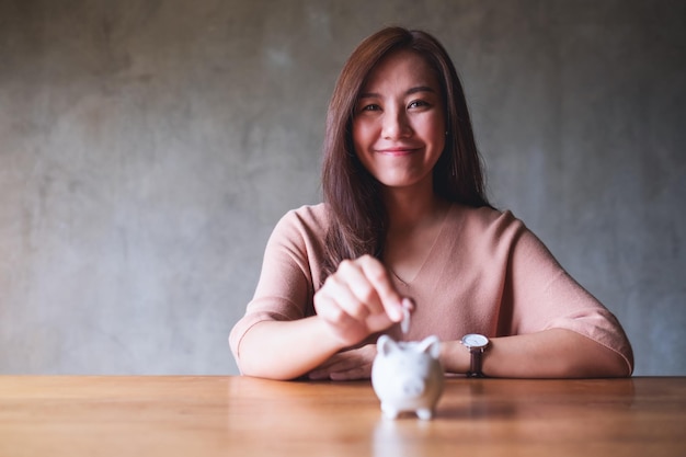 A young asian woman putting coins into piggy bank for saving money concept