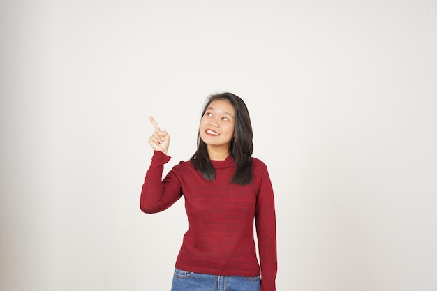 白い背景に隔離されたサイドコピースペースを指している赤いTシャツを着た若いアジア人女性