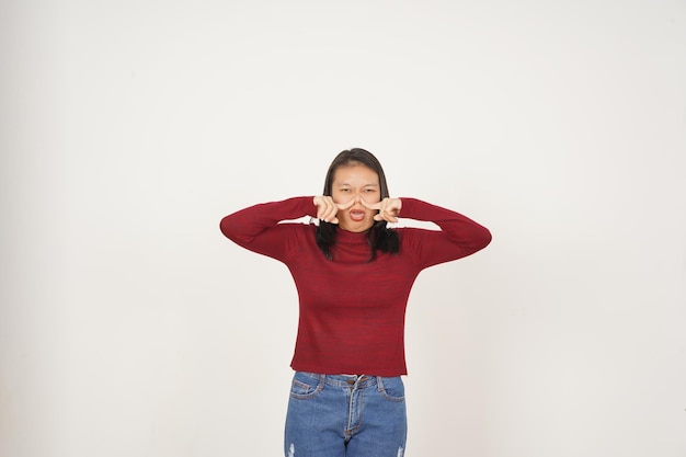 Young Asian woman in Red tshirt Smelling something stinky and disgusting isolated on white background