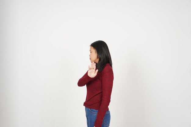 Молодая азиатка в красной рубашке Остановление жеста рукой Концепция отвержения изолирована на белом фоне
