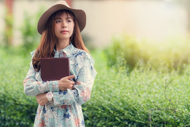 Young asian woman in retro style with a book strolling in park