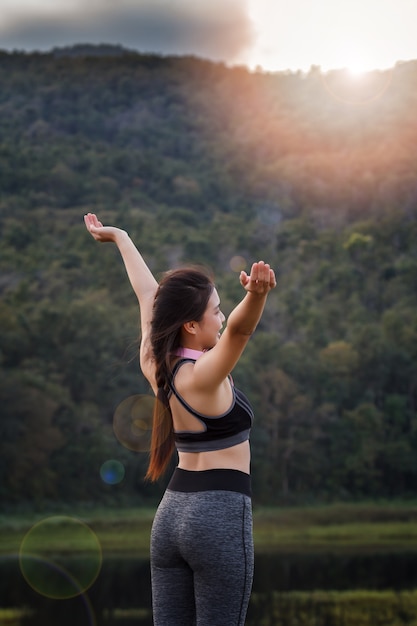 Young asian woman runner raise her hand up to resting after workout session