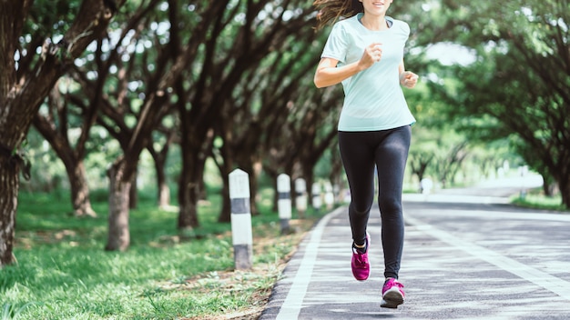 Young asian woman running on road in the nature.