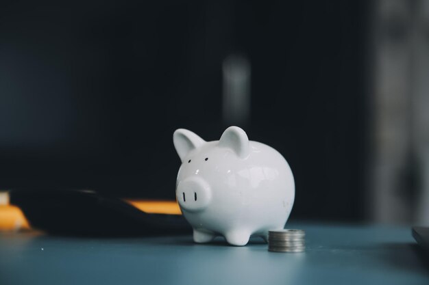 Young Asian woman saving for retirement Saving money through a piggy bank and taking notes on notebook savings concept