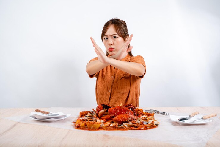 若いアジア人女性はシーフードカニのパダンソースを食べることにノーと言う