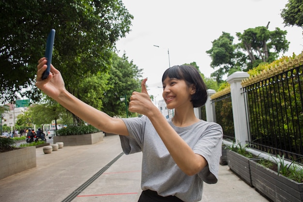 公共の場で携帯電話と若いアジアの女性のselfie