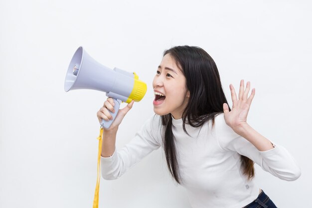 Молодая азиатская женщина кричит и кричит с мегафоном на белом фоне с копией пространства