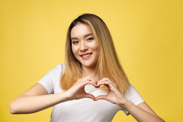Молодая азиатская женщина показывает знак рукой сердца