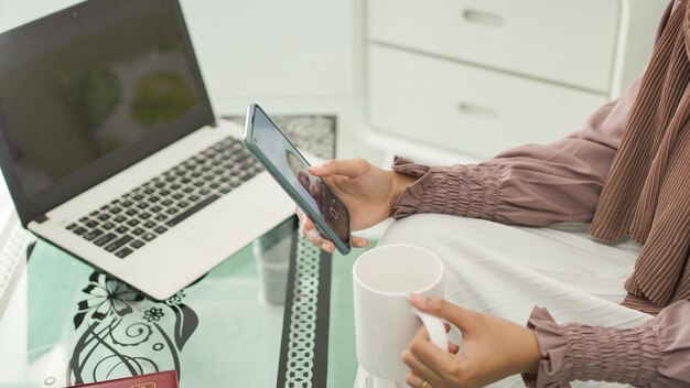 Young asian woman sitting at home enjoying a drink while video calling