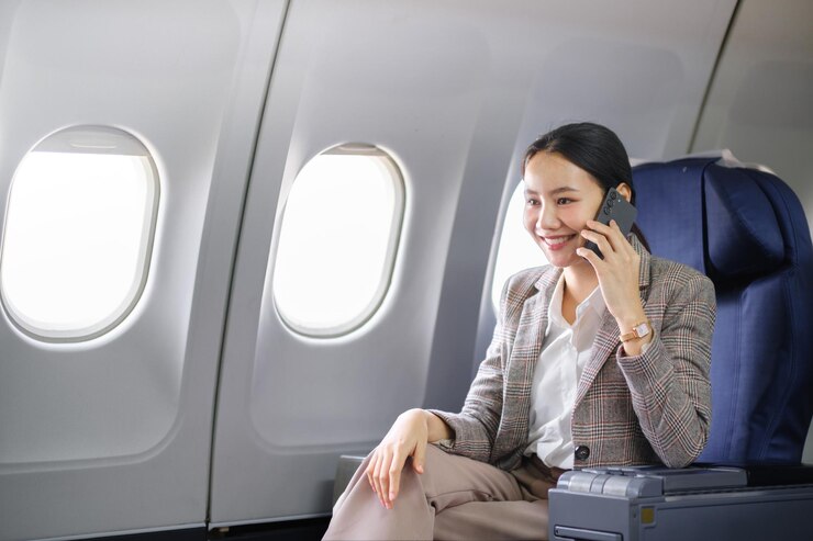 Photo 飛行機の座席に座ってスマートフォンで話している若いアジア人女性若い女性旅行者