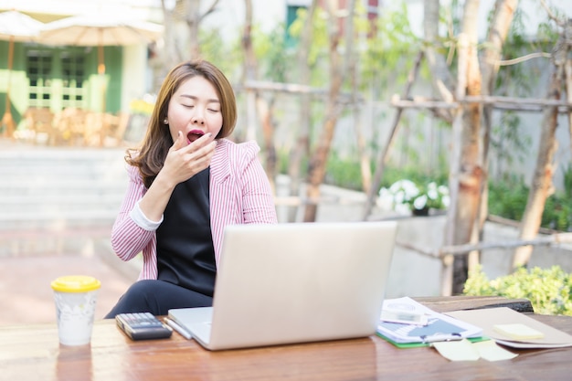 Young Asian woman sitting at table in front of laptop