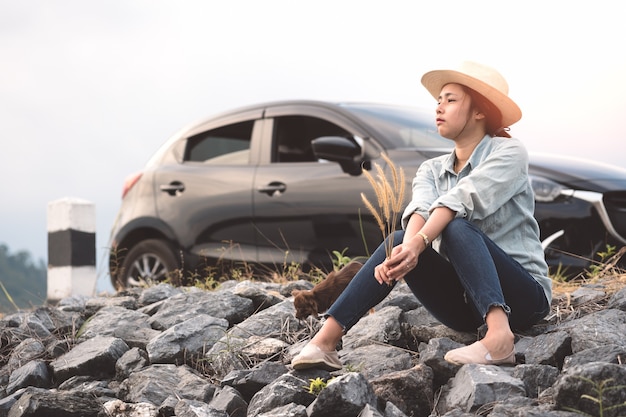 Young asian woman sitting with chihuahua dogs with black hatchback eco car.