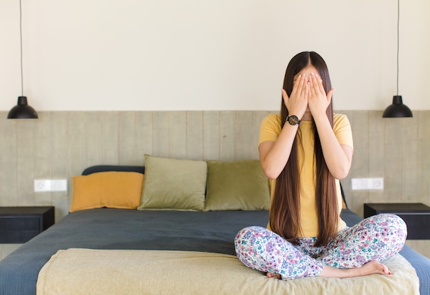 Young asian woman smiling and feeling happy, covering eyes with both hands and waiting for unbelievable surprise