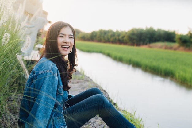 笑顔の若いアジア人女性。美しい自然で日没を楽しむ少女。