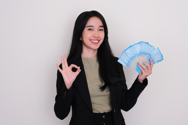 Young Asian woman smiling and give OK finger sign while holding money