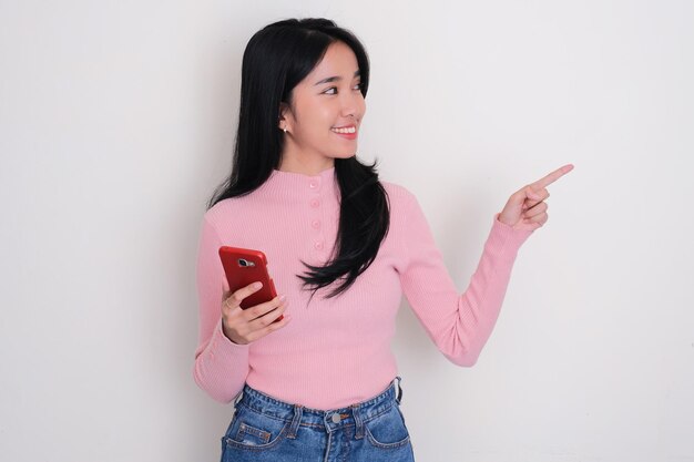 Young Asian woman smiling and looking to the left side while holding mobile phone