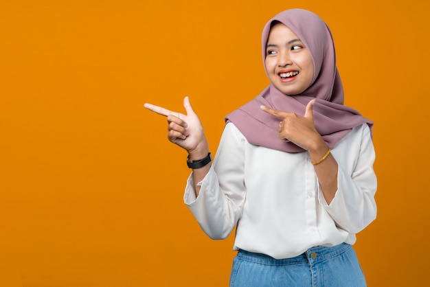 Young asian woman smiling and pointing to empty space