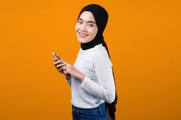 Young asian woman smiling and using mobile phone