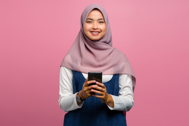 Молодая азиатская женщина улыбается с помощью мобильного телефона