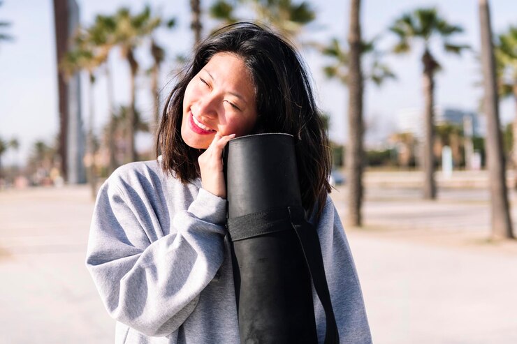 Photo ヨガマットを握りながら微笑む若いアジア人女性