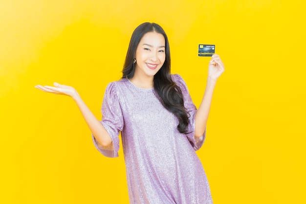 young asian woman smiling with credit card on yellow