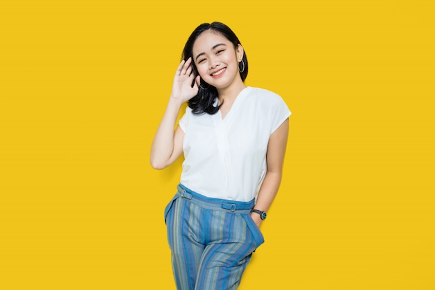 Young asian woman smiling on yellow wall