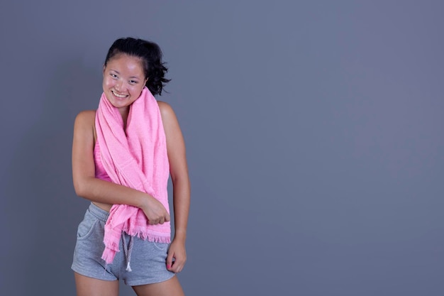 Young asian woman in sportswear with towel around her neck isolated from the background