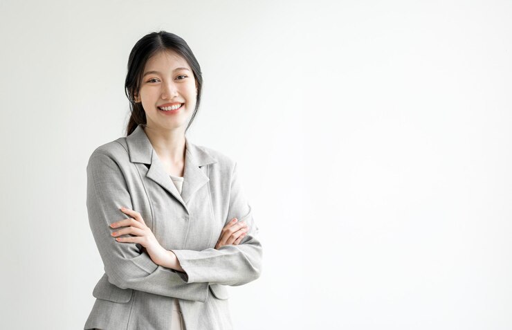 Photo 사무실에 서서 웃고 자신감 있는 흰색 배경을 바라보는 젊은 아시아 여성