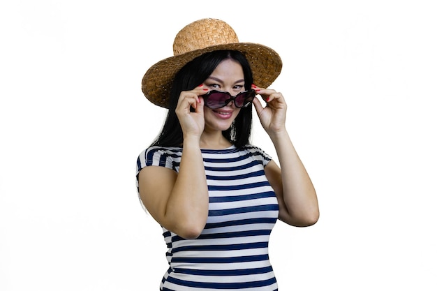 ストローの帽子をかぶった若いアジア人女性が白い上に隔離されたサングラスを着ています