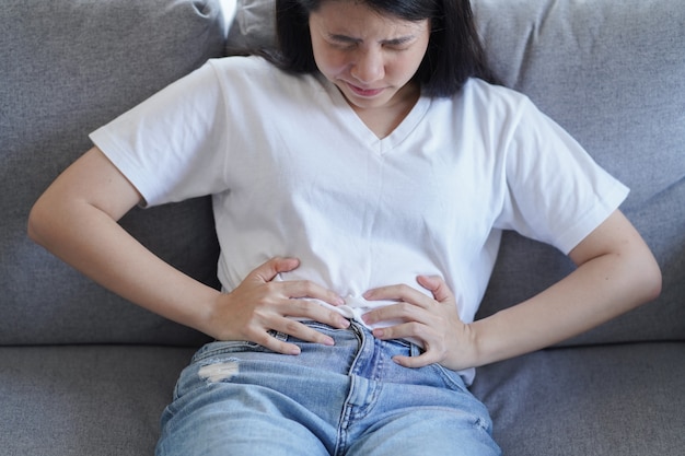 Foto giovane donna asiatica che soffre di forti dolori addominali