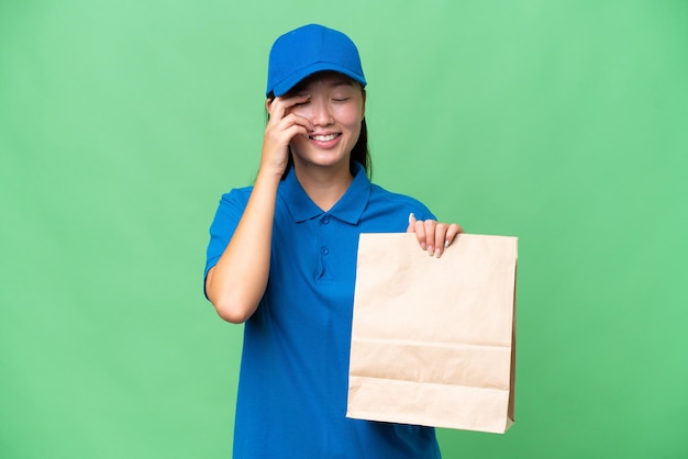 Young Asian woman taking a bag of takeaway food over isolated background laughing