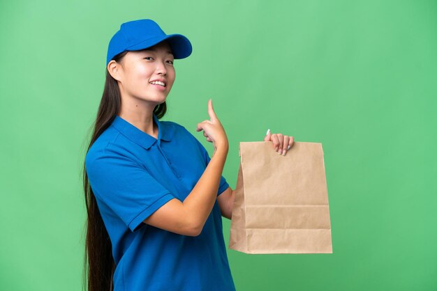 외진 배경 위에 테이크아웃 음식을 들고 있는 젊은 아시아 여성