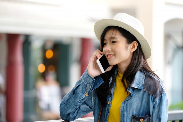 アジアの若い女性、都市の屋外で電話を取る、都市のライフスタイルで携帯電話の人々