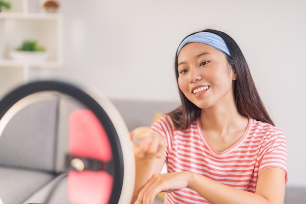 Young asian woman taking pictures with her cell phone on a tripod