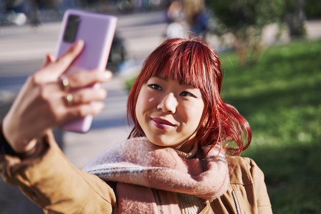 携帯電話で自分撮りをするアジアの若い女性