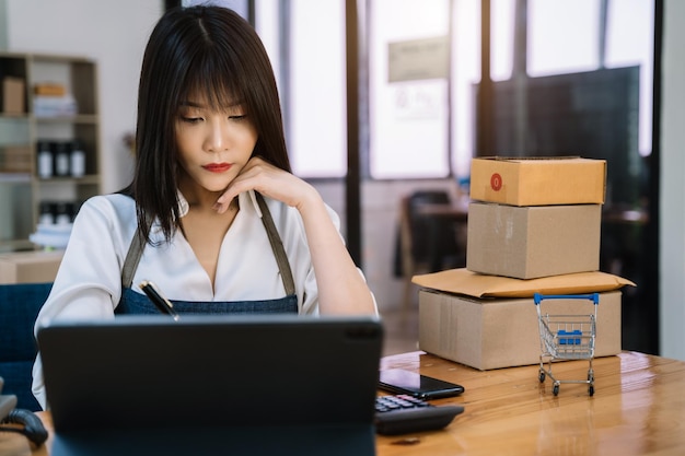 Young asian Woman Thinking and Working on sell online in cozy house Modern Lifestyle of New Generation People