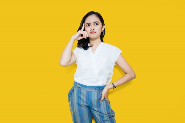 Young Asian woman thinks idea on yellow wall