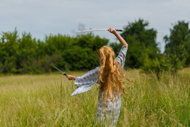 Young asian woman in traditional kimono trains fighting techniques with katana sword outdoors, samurai warrior girl