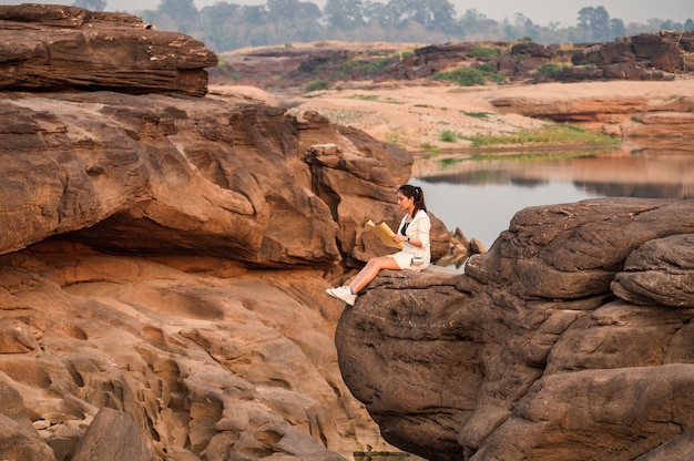 Photo young asian woman traveler looking at paper map on rock cliff in grand canyon of thailand